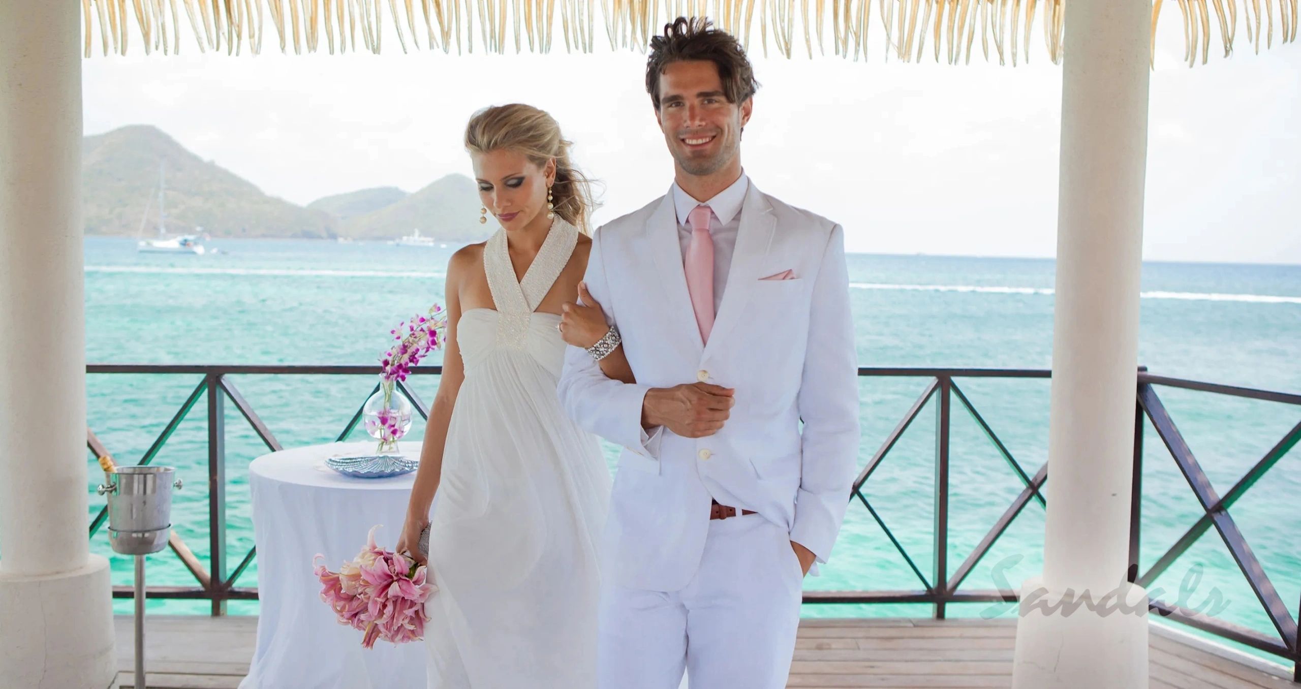 Newlyweds on a balcony overlooking turquoise water