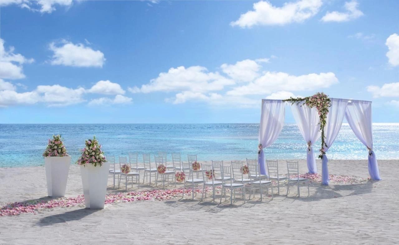 White beach ceremony chairs and a draped oceanfront arch