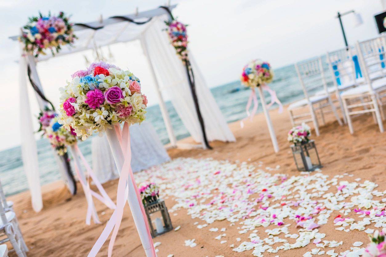 Beach wedding aisle lined with colourful flowers