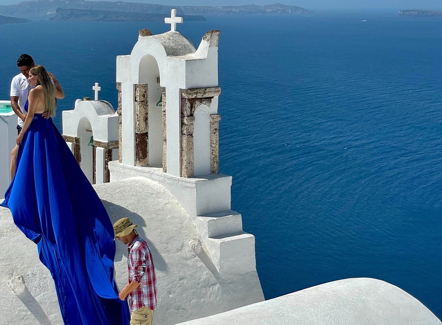 Couple beside a white chapel overlooking the sea