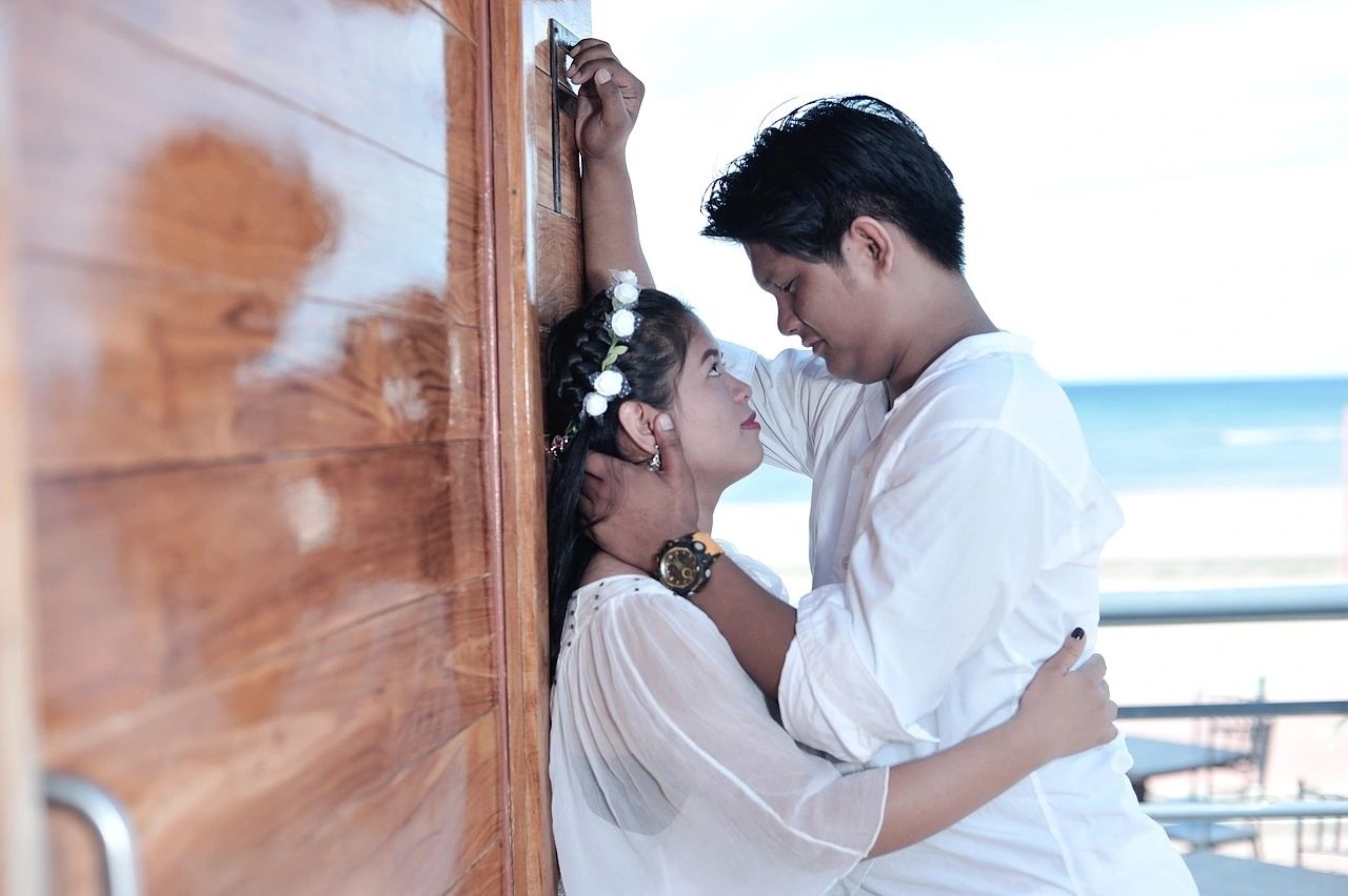 A couple gazing at each other with the ocean in the background