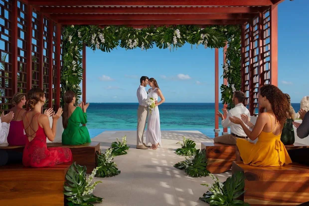 Wedding couple beneath a tropical pergola facing the ocean