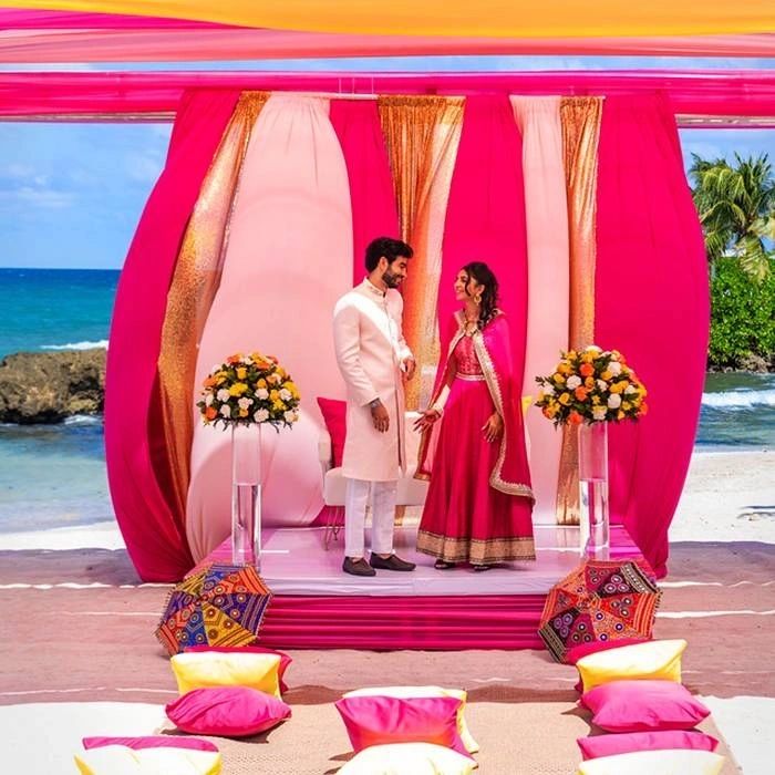 South Asian beach wedding mandap with pink and yellow drapes