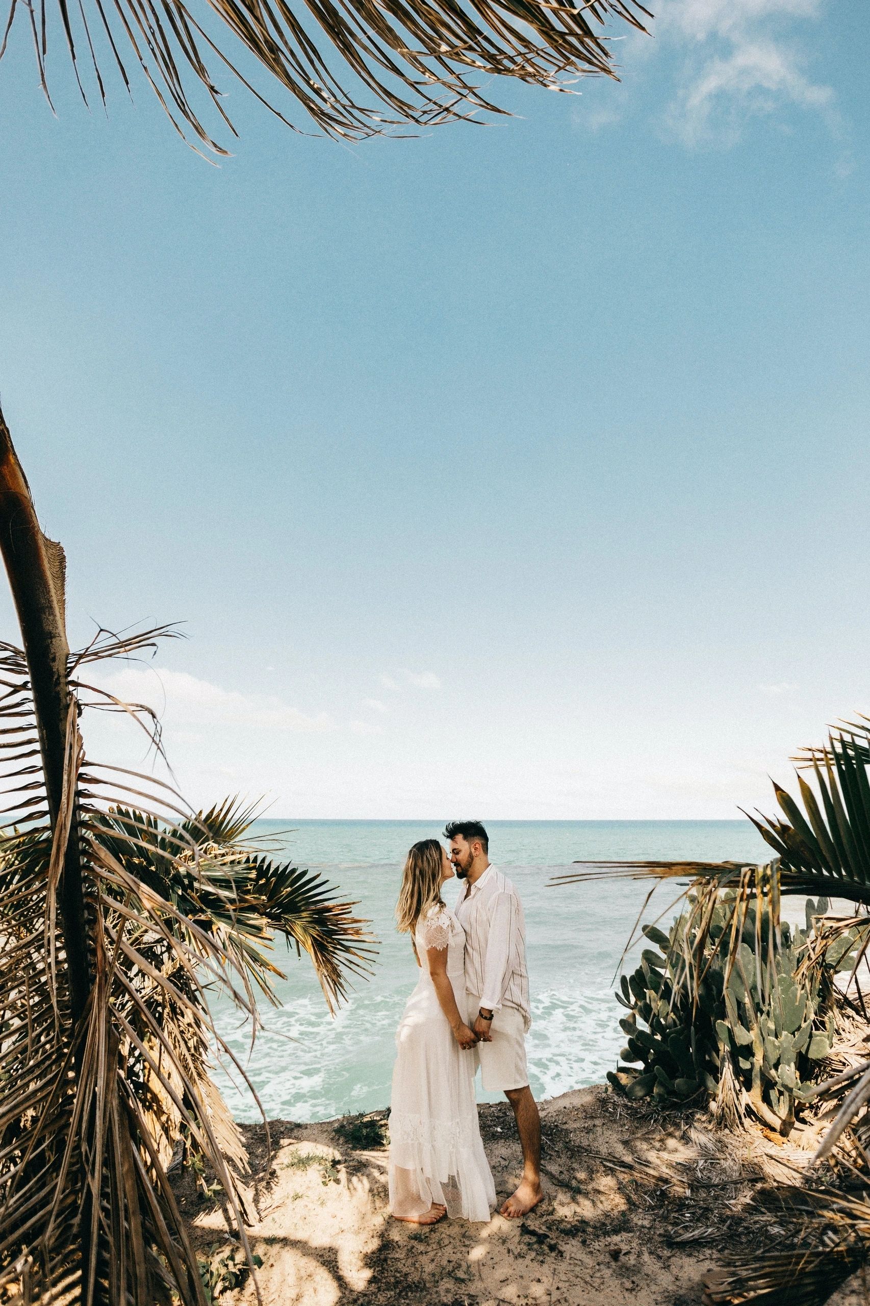 Couple celebrating beside tropical greenery and the sea