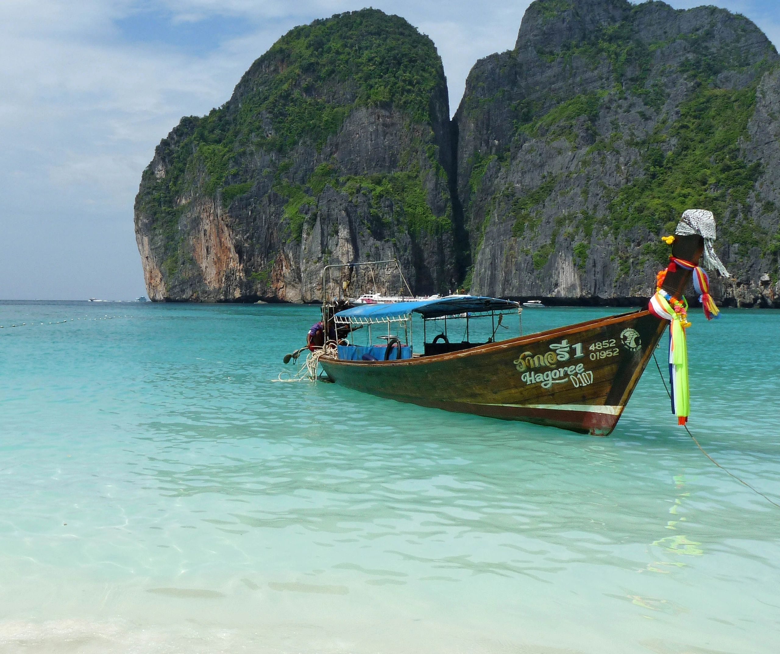 Long-tail boat beside limestone cliffs in Thailand