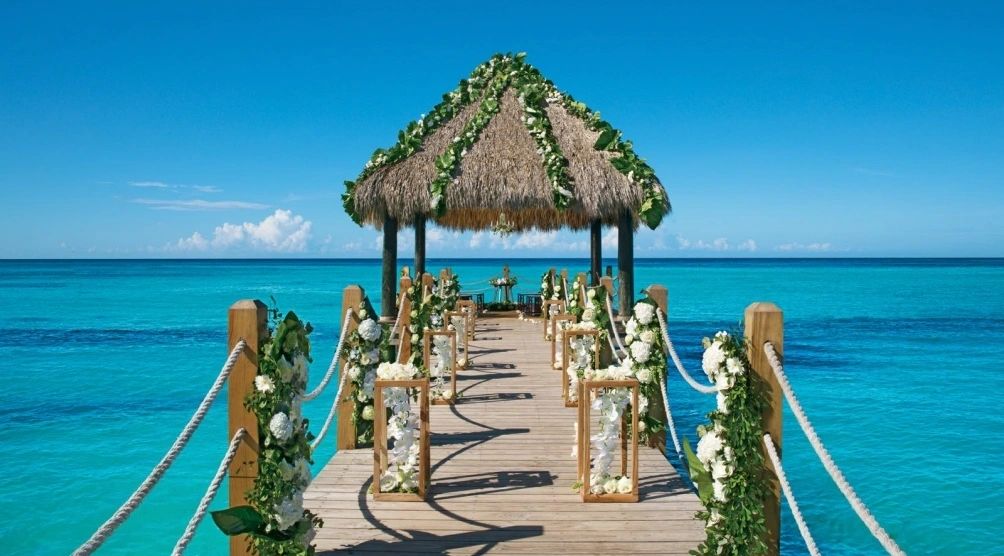 Flower-lined pier leading to an overwater wedding gazebo