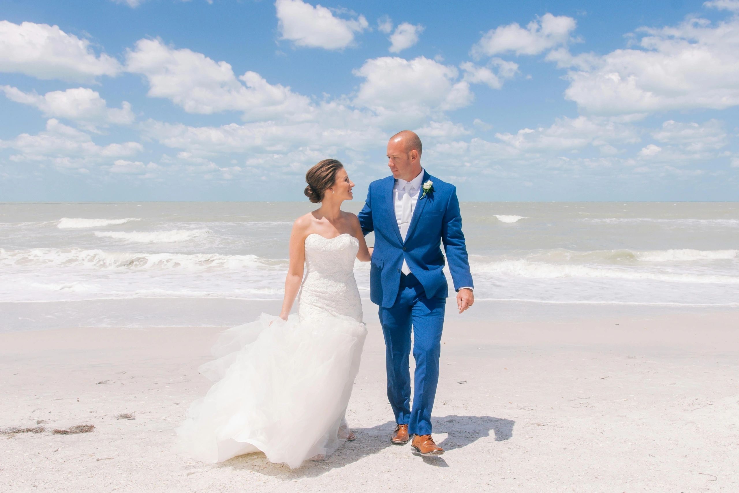 Newlyweds walking together on a white-sand beach