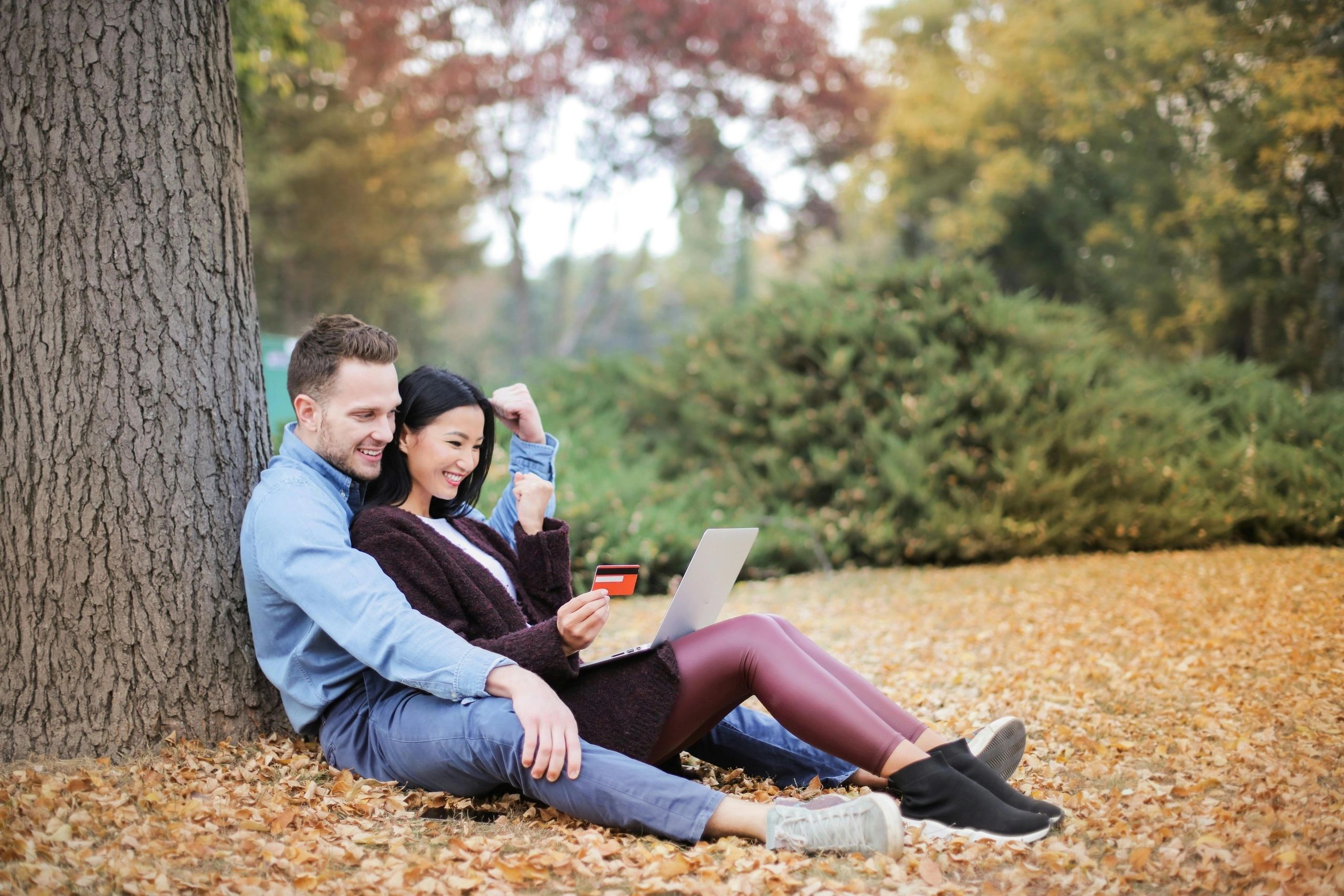 Couple relaxing together against a tree in a park