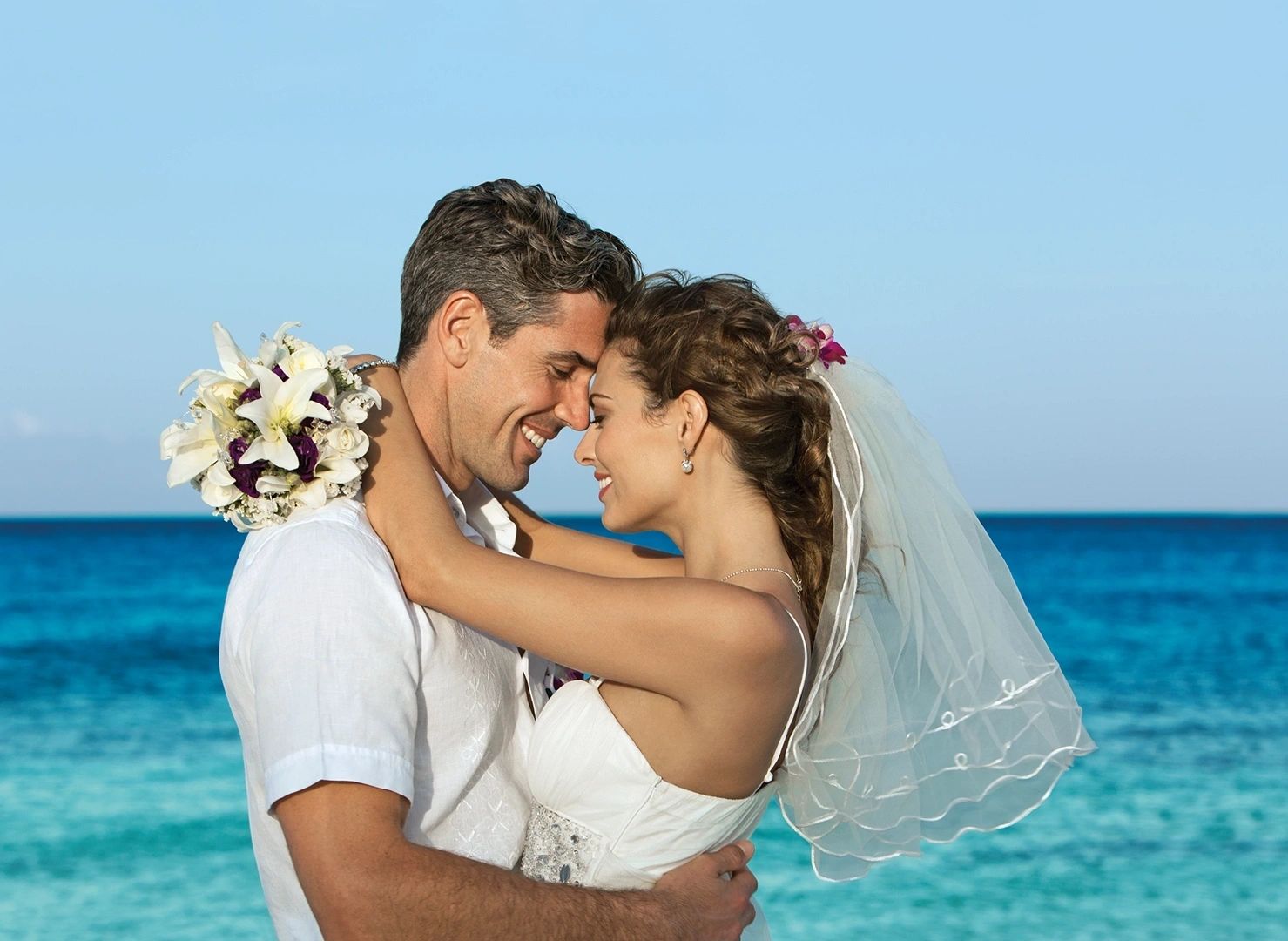 Newlyweds embracing beside the ocean