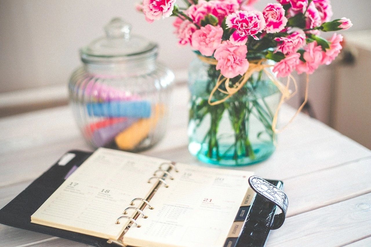 Wedding planning notebook beside pink flowers