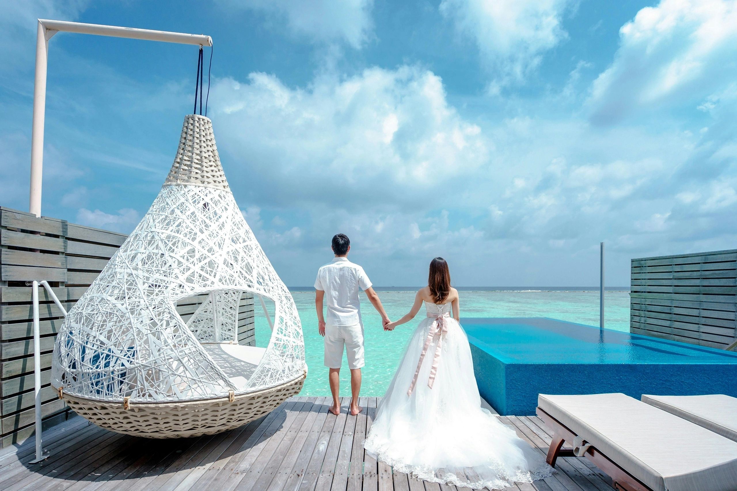 Newlyweds beside a pool overlooking the ocean