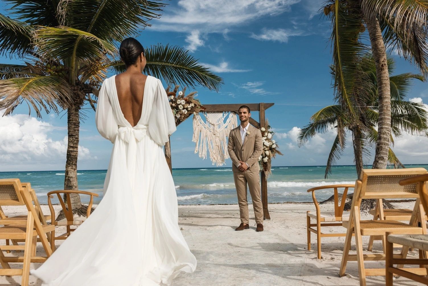 Couple walking towards a palm-lined beach ceremony