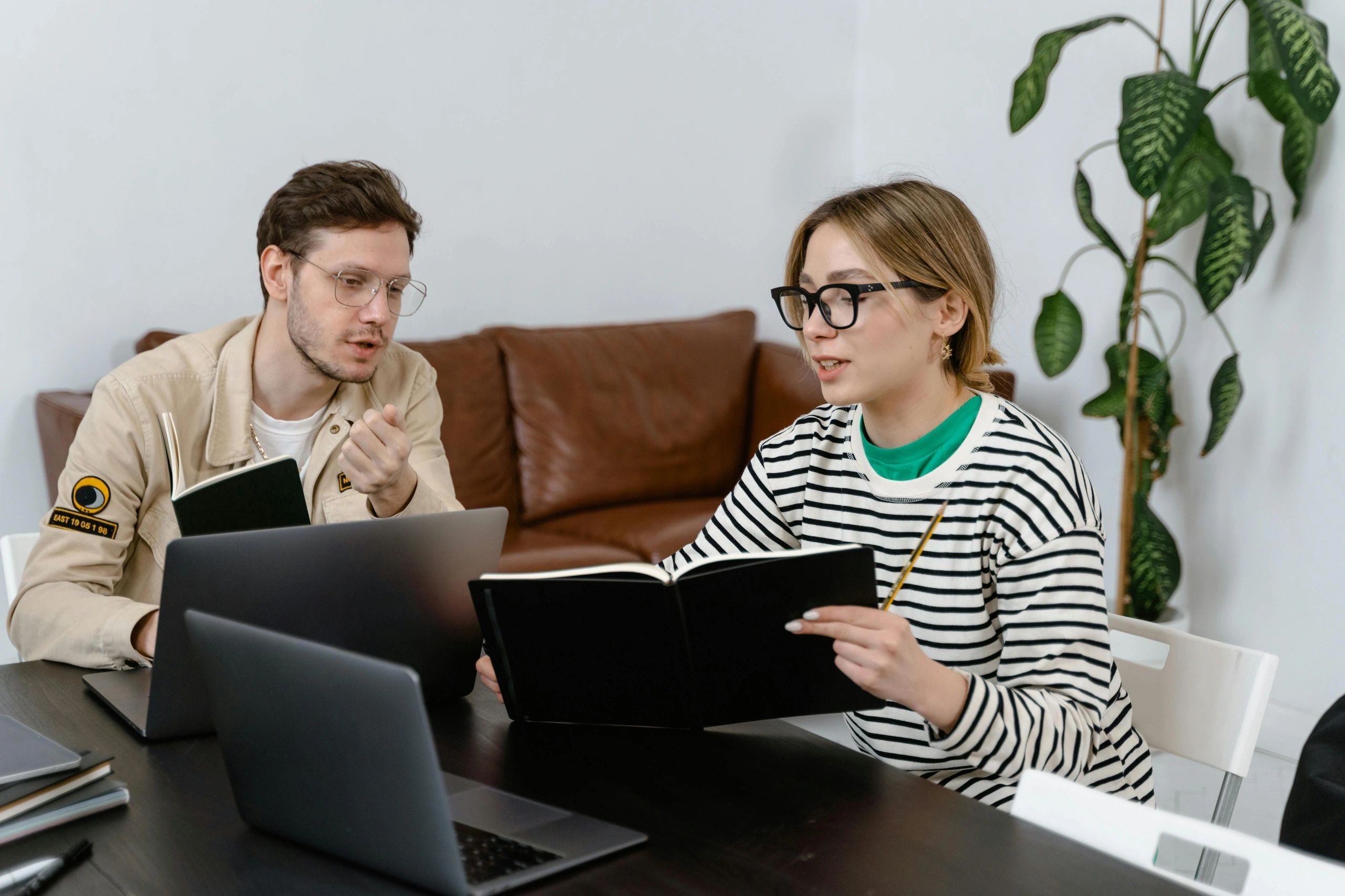 Couple reviewing travel plans with a laptop and notebook