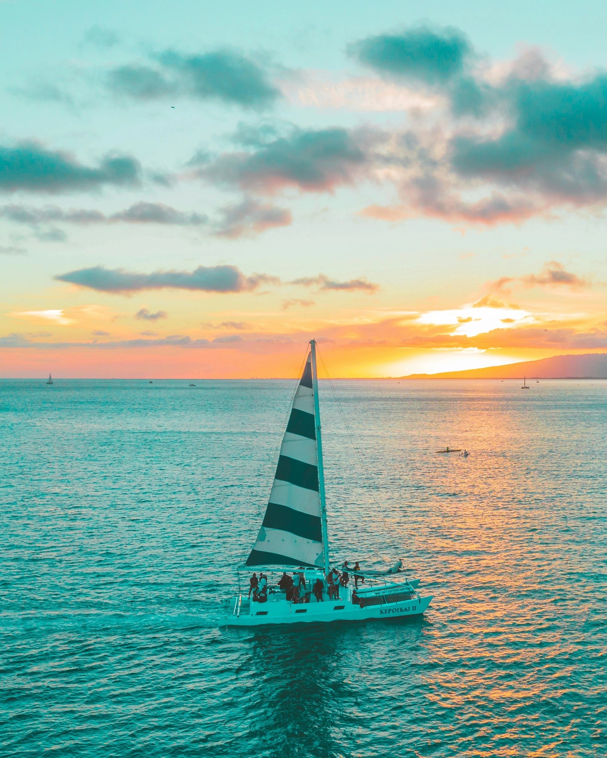 Sailboat on turquoise water at sunset