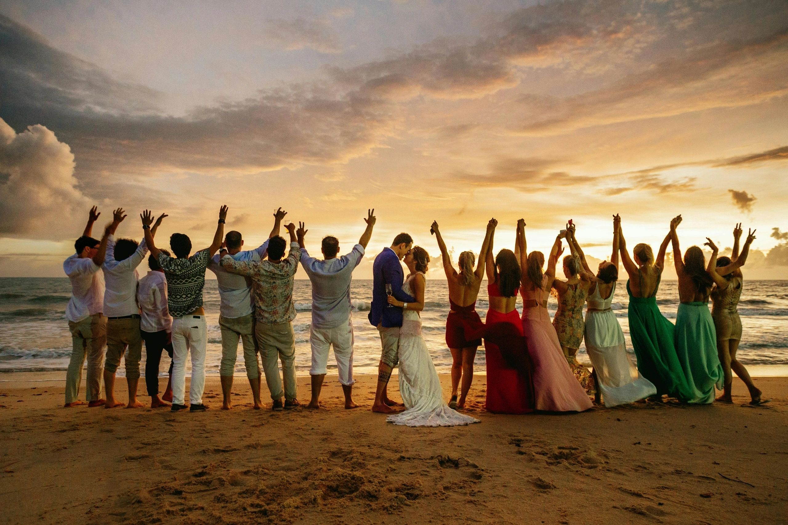 bride groom with wedding guest on beach at sunset
