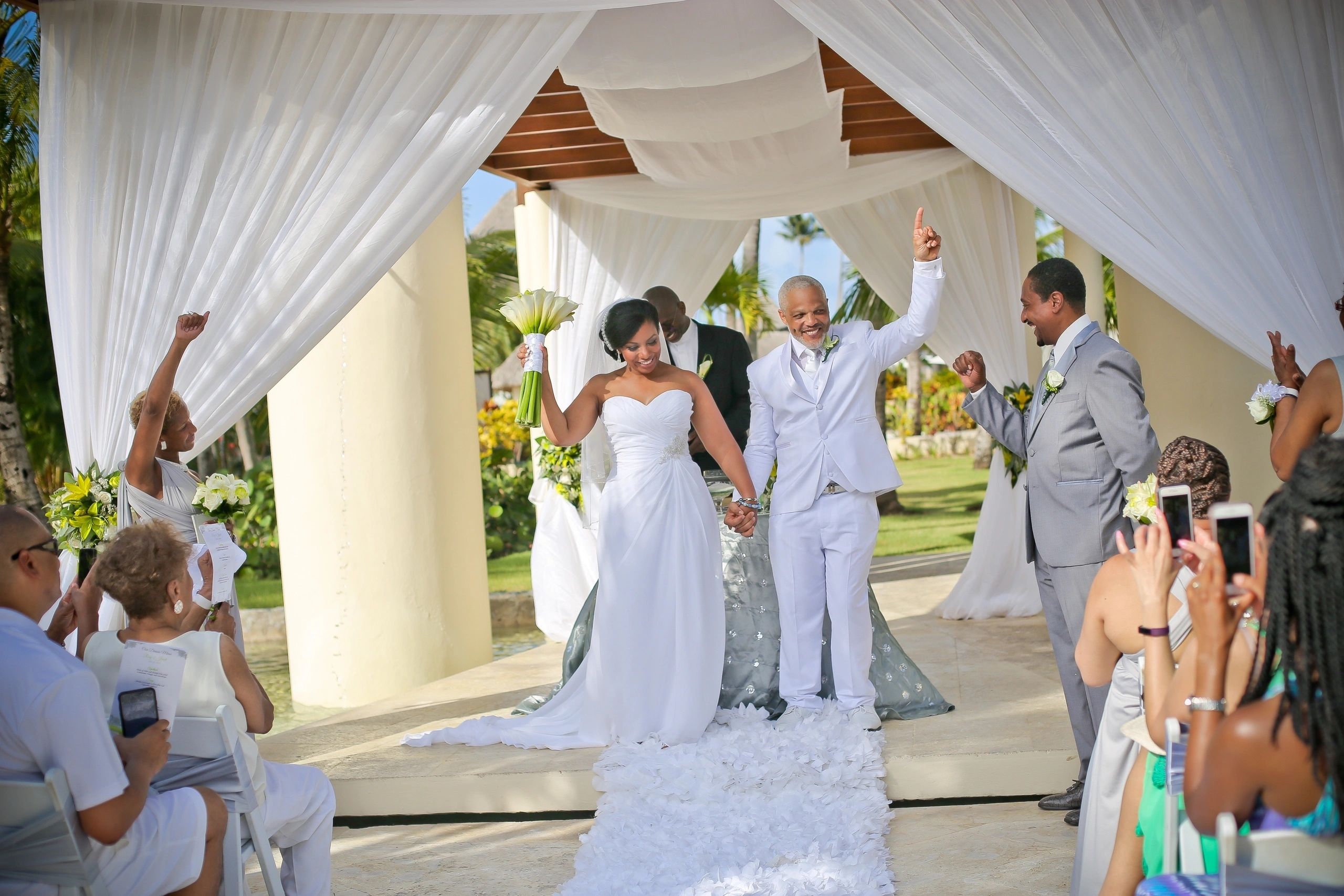 Wedding couple and guests beneath a draped ceremony canopy