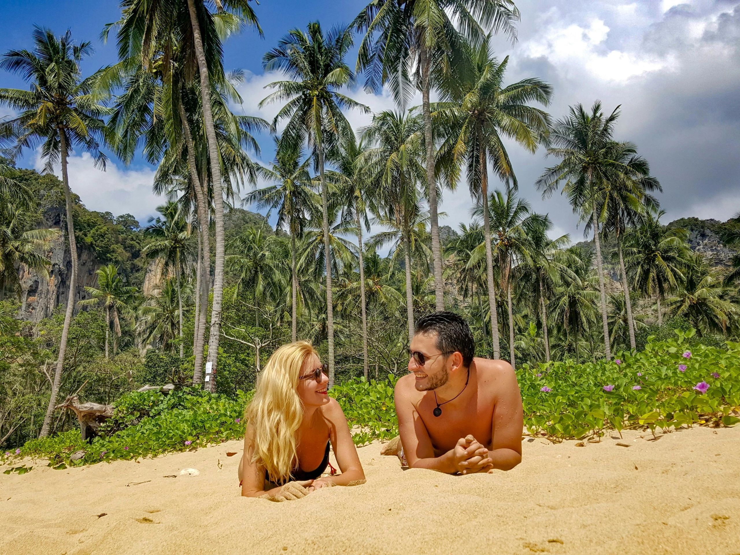 a couple laying on a beach with palm trees in the background
