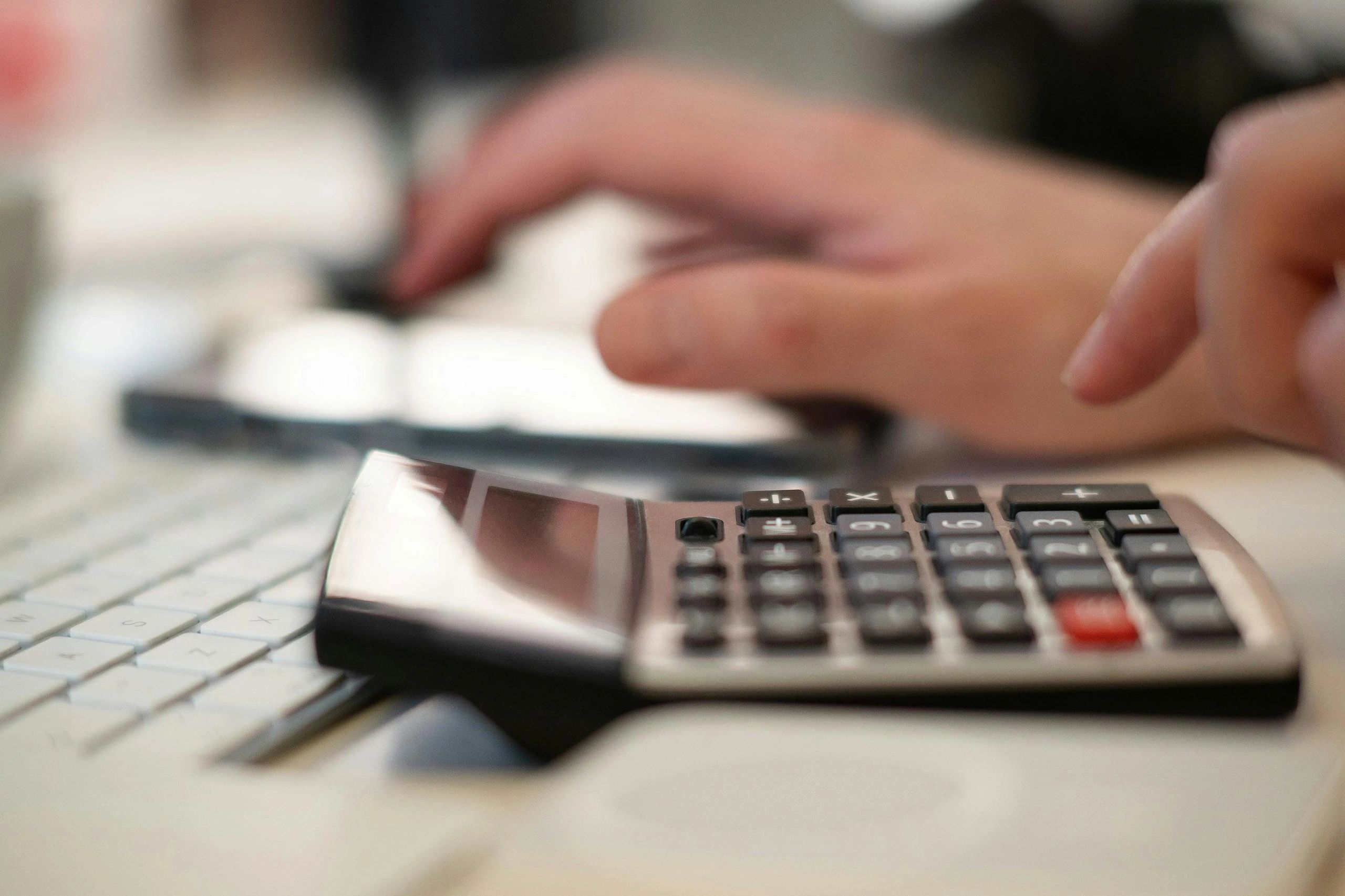 Hands working with a calculator and travel budget paperwork