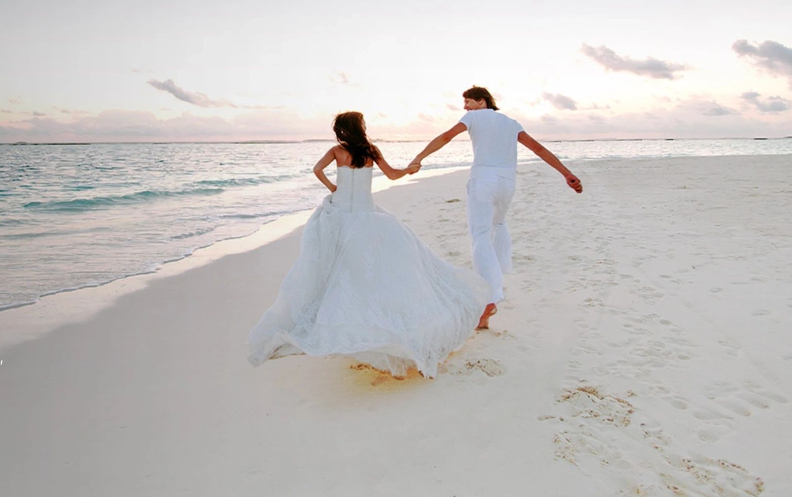 Newlyweds walking beside the surf at sunset